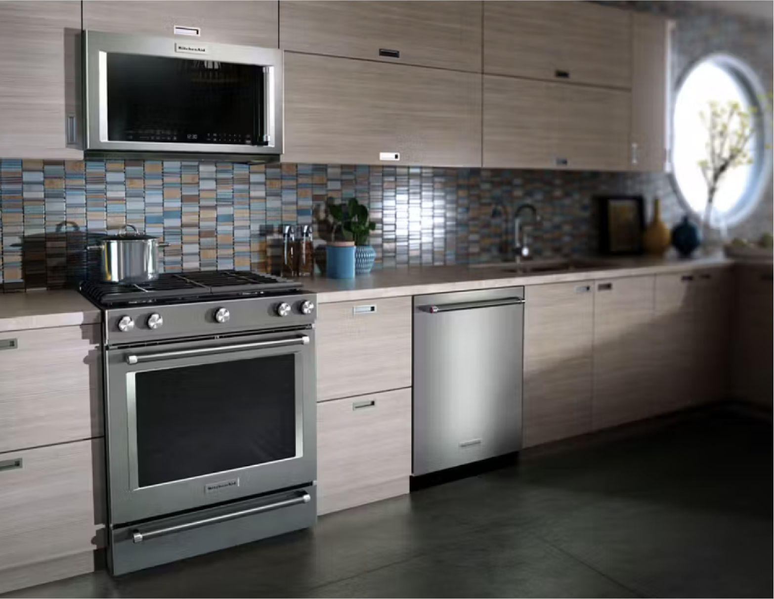 kitchenaid oven next to a kitchenaid dishwasher in a kitchen with lightwashed wooden cabinets